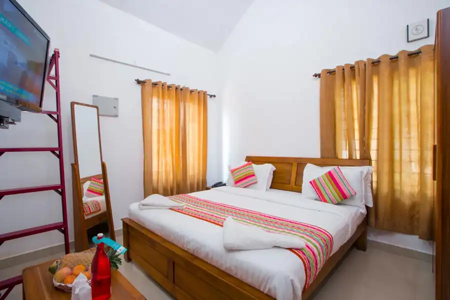 Deluxe Valley View Room at Misty Lake Resort with elegant interiors, cozy bedding, and large windows overlooking the misty green valleys of Munnar.