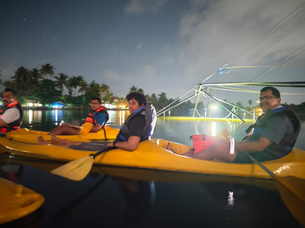 Friends enjoying kayaking together in the serene backwaters of Kochi under the evening sky.