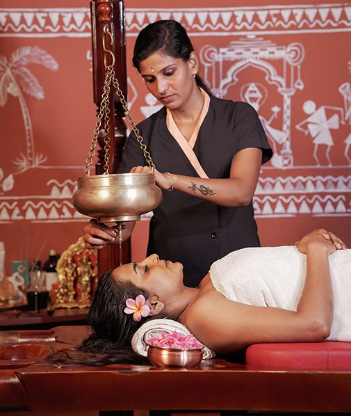 Ayurveda therapy at Akanta Ayurveda & Yoga Cherai, Kerala, with warm herbal oil gently poured on the forehead in a serene treatment room