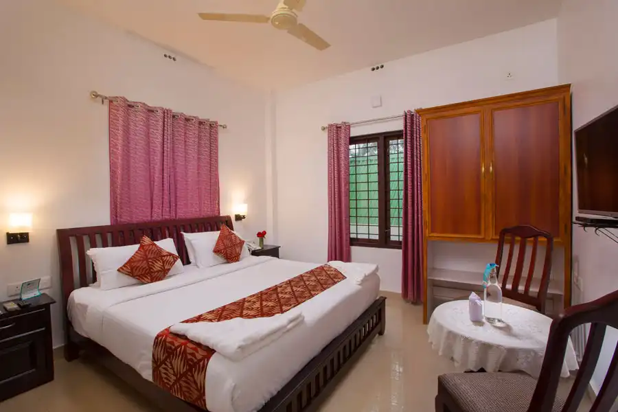 “Cozy bedroom in Misty Lake Resort, Munnar with private balcony and misty hill views”