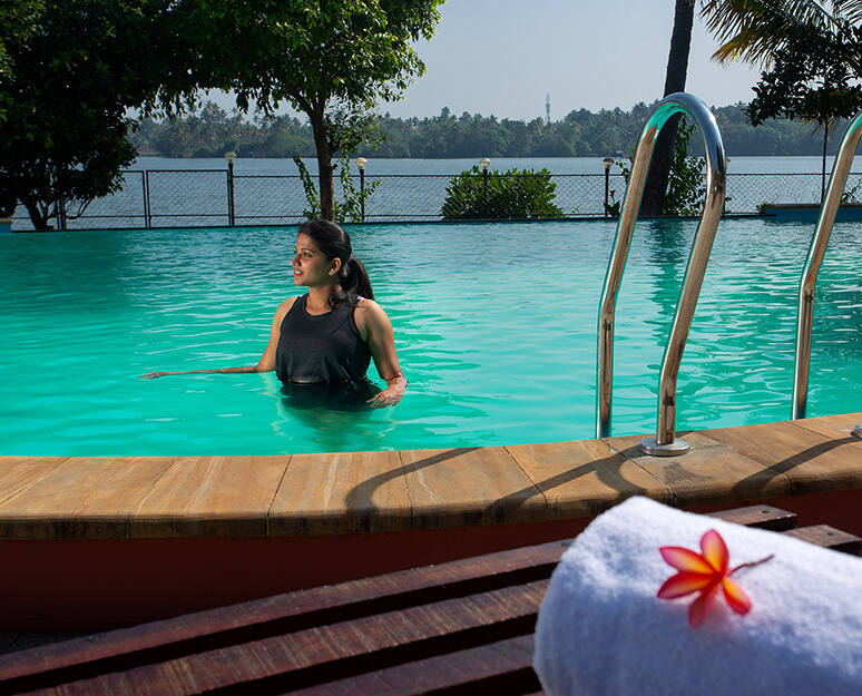 “Swimming pool at Akanta Ayurveda & Yoga Cherai resort surrounded by lush greenery and tranquil ambiance”