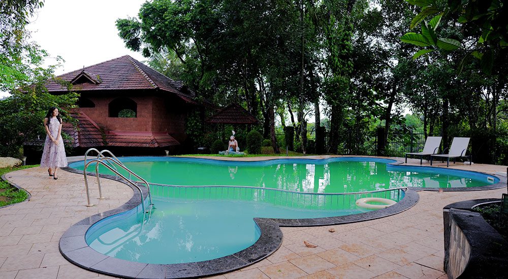 Swimming pool at Indeevara Retreat Wayanad surrounded by lush greenery and forested hills