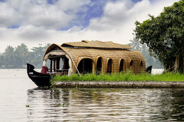 A luxury Kerala houseboat showcasing a fine blend of traditional wooden design and modern comforts, set against serene backwaters.