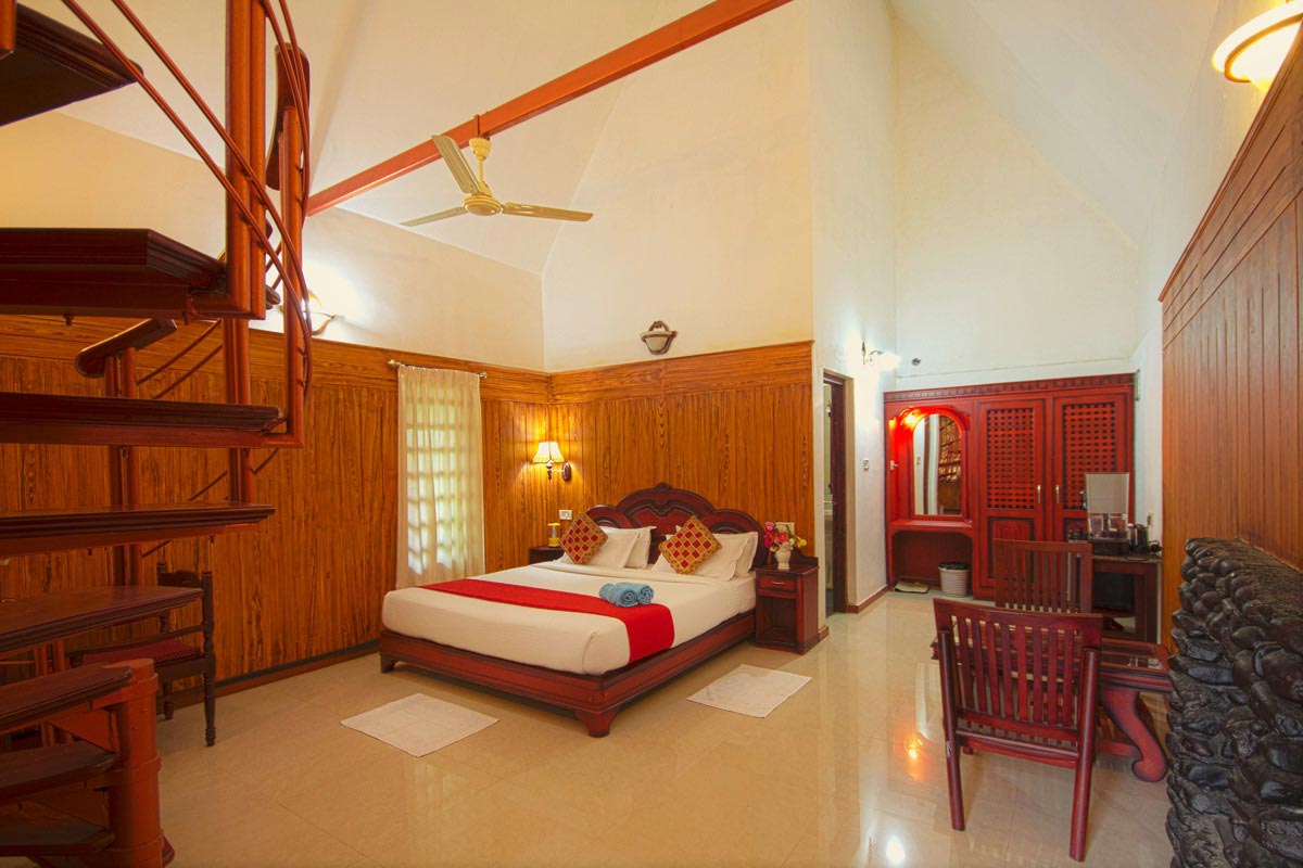 Cozy western-style cottage with inviting lofts and a warm fireplace, nestled amidst nature with scenic views of lush green landscapes and cascading waterfalls in Coorg.