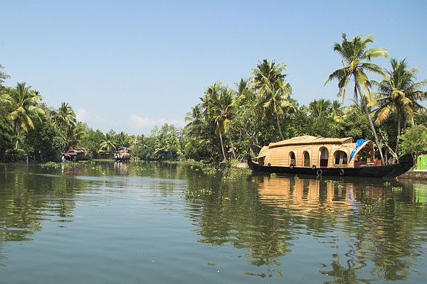 Luxury houseboat cruising through the serene backwaters of Alleppey surrounded by coconut trees”