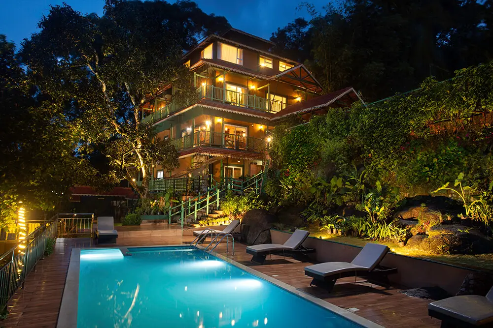 Swimming pool at Bamboo Dale Munnar surrounded by lush greenery and hills