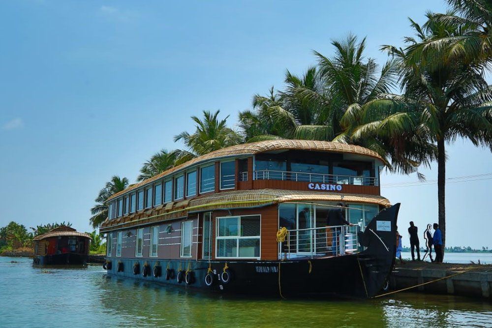 Traditional Kerala houseboat cruising through the tranquil backwaters of Alleppey surrounded by lush greenery.