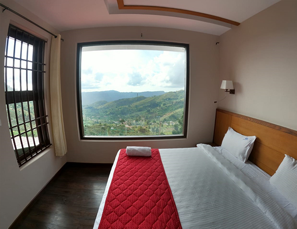 Valley View Room at Warmth Hill Crest in Kodaikanal featuring elegant interiors, cozy bedding, large windows overlooking lush green valleys, and modern amenities ideal for a family resort in Kodaikanal.