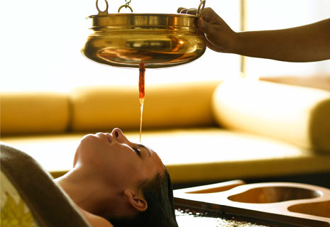 Authentic Ayurveda therapy session at Warmth Lake Haven Island Resort, one of the finest ayurveda resorts in Alleppey, featuring traditional herbal oil treatment in a serene backwater setting.