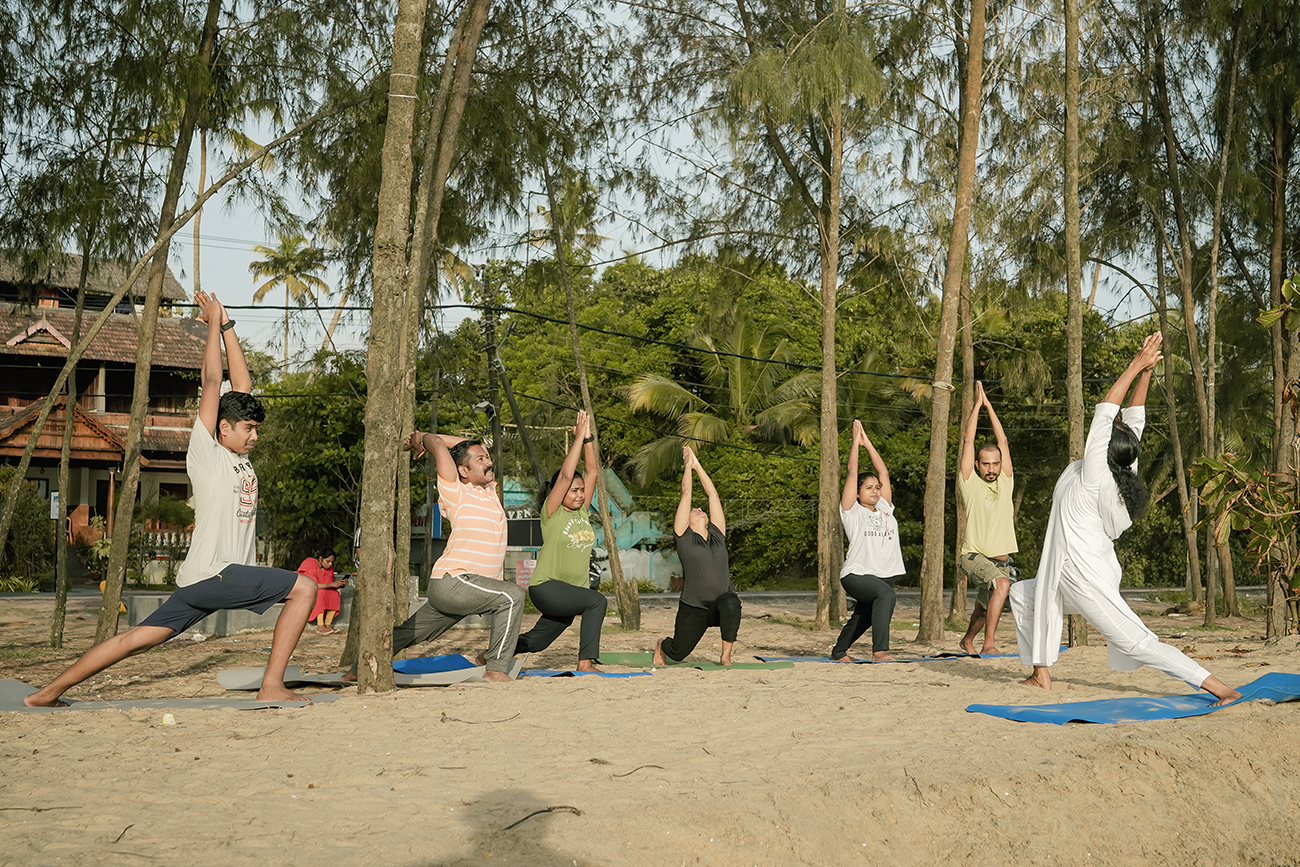 Guests practicing yoga at sunrise on Cherai Beach at Akanta Ayurveda & Yoga Cherai, Kerala.