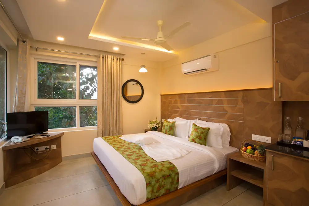 Luxury bedroom at Amrezy Resort & Spa Vythiri featuring elegant interiors, a comfortable king-size bed, warm lighting, modern amenities, and scenic views of the misty hills of Wayanad.