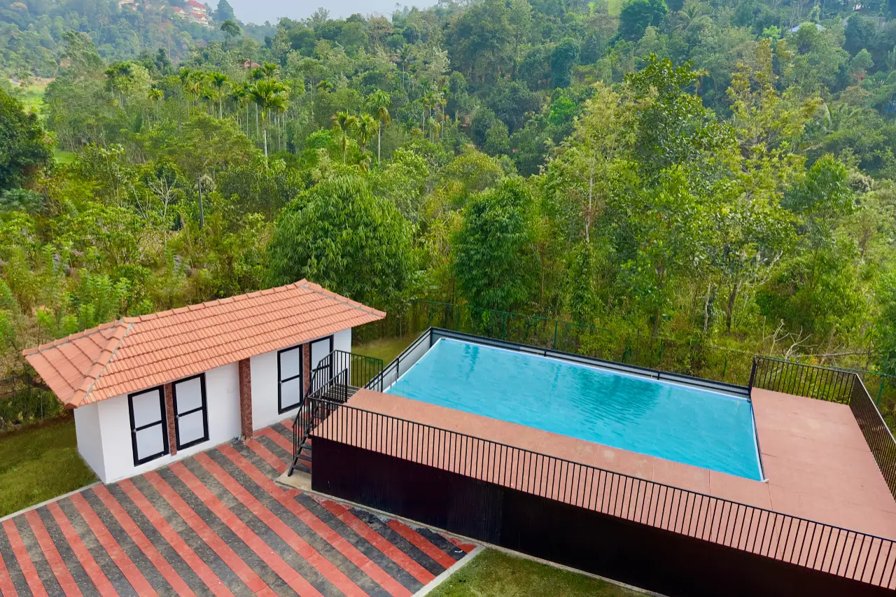 Scenic swimming pool at Heaven Inn Munnar surrounded by misty hills and lush greenery