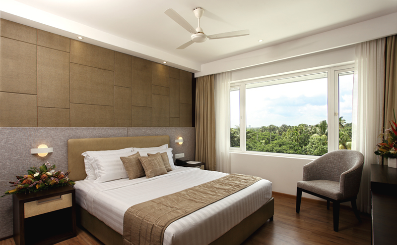 Elegant executive bedroom at Sugar Business Hotel featuring modern interiors, premium bedding, ambient lighting, and sophisticated business-class comfort in Kochi.
