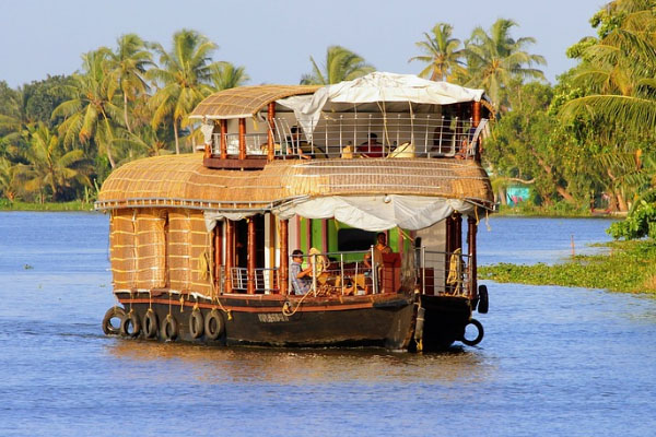 Cruiseland luxury houseboat cruising through the scenic Alleppey backwaters surrounded by coconut palms and tranquil waters