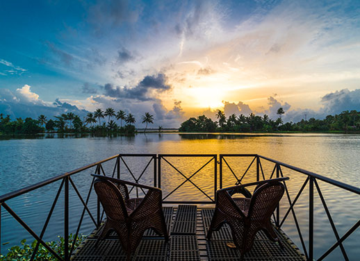 Guests enjoying a river cruise in Alleppey, experiencing the freshness of the river, scenic backwaters, and traditional village life along the shoreline.