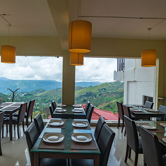 Hill-view dining space at Warmth Hill Crest, Kodaikanal, offering panoramic valley views and a wide variety of delicious cuisines in a peaceful mountain setting.